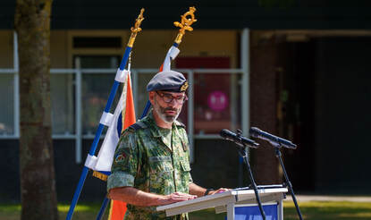 Een militair staat achter een spreekgestoelte.