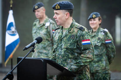 Een militair spreekt vanachter een spreekgestoelte.