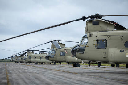 Chinooks en Apaches achter elkaar in een lange rij opgesteld.