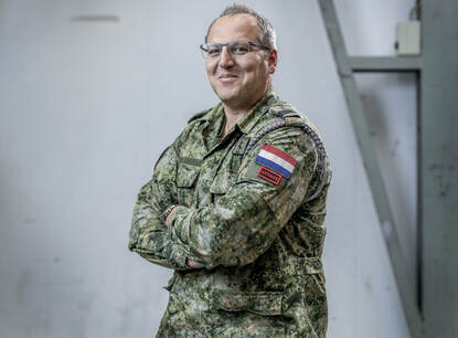 Portret van militair met bril op en armen over elkaar.