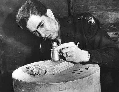 Een militair bekijkt een ontsteker van een bom van dichtbij.