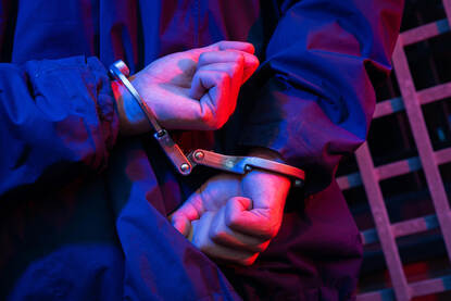 2 handen met handboeien om.