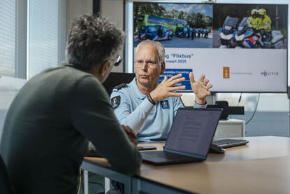 Twee mannen in gesprek aan kantoortafel.