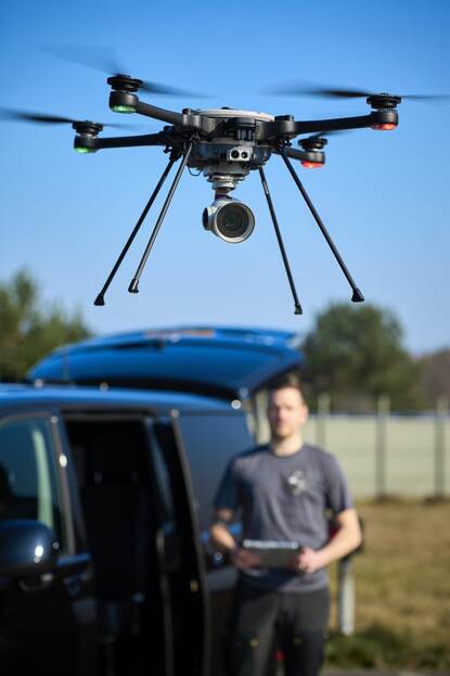 Een vliegende drone met vaag op de achtergrond de operator.