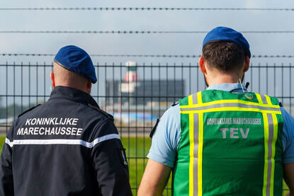 Twee marechaussees op de rug gezien bij de luchthaven