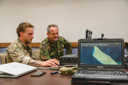 Twee militairen achter een laptop in een commandopost.