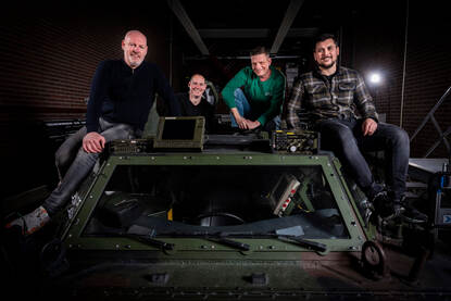 Groepsfoto van het integratie testteam (ITT) van JIVC/Landgebonden IT op een Fennek verkenningsvoertuig