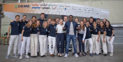 Studenten van de TU Delft poseren met John Williams voor hun waterstofboot.