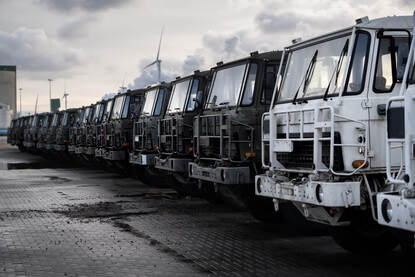 Tele-opname van een lange rij naast elkaar geparkeerde viertonners op de kade in de Eemshaven.