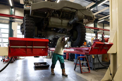 Monteur sleutelt aan halftrack-voertuig op een brug.