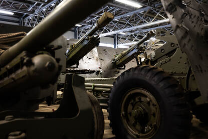 Stukken artillerie op elkaar in een loods.
