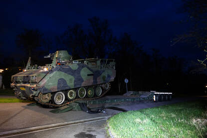 YPR-765 rijdt op een dieplader in de schemer.