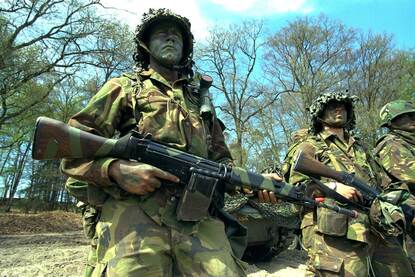 Drie cecamoufleerde militairen met FAL op oefening.