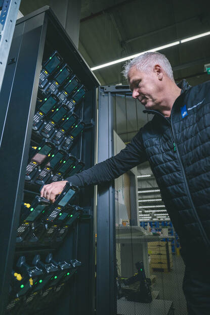 Coördinator Centraal Kledingpunt Marco haalt een scanner uit de brandwerende kast. Overdag kunnen daar de batterijen opladen.