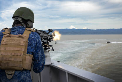 Vier foto’s met een vlootcollega die op een bootjes schiet, een gewonde marinier die medisch wordt geholpen en collega’s aan het werk in de kombuis.