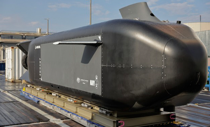 Een aantal mensen met een paraplu staan bij een model van de Ghost Shark.