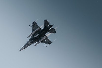 Een schutter schiet gesimuleerd met een Tracking Head Trainer op een F-16  van de Griekse luchtmacht op de NATO Missile Firing Installation (NAMFI). Foto ernaast: Een F-16 in de lucht.